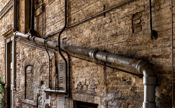 Pipes on a weathered brick wall in an alley