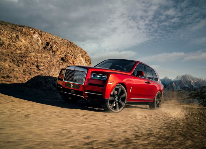 Red Rolls-Royce Cullinan SUV driving on dirt road