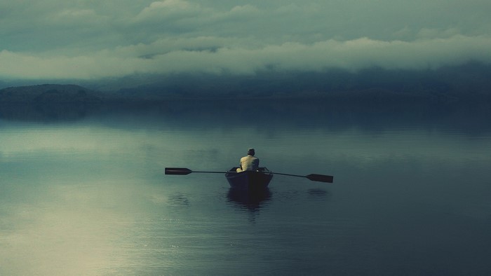 Man rowing a boat on a misty lake