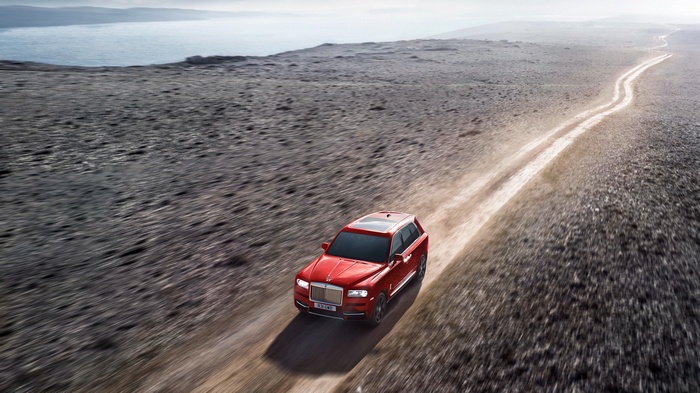 Red 2019 Rolls-Royce Cullinan SUV driving on dirt road