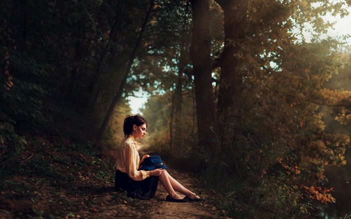 Woman sitting in a forest with a hat