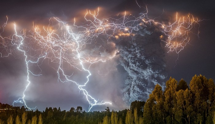 Lightning strikes during a volcanic eruption over trees