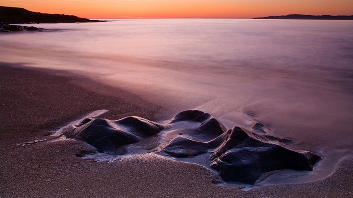 Beach at sunset with rocks and ocean