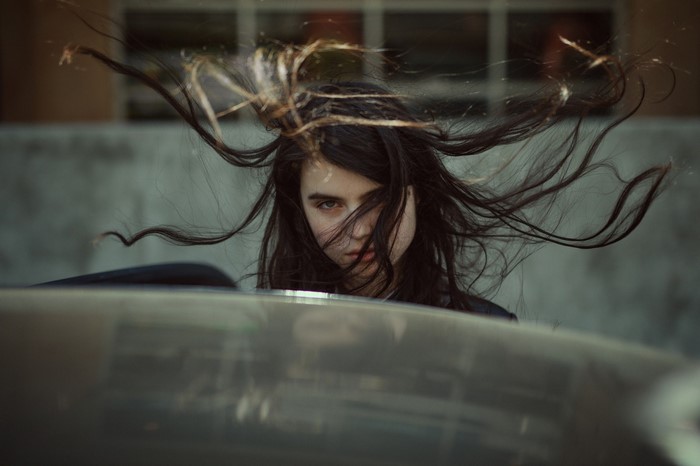 Woman with windblown hair in front of a car
