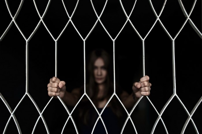 Woman behind a white metal fence