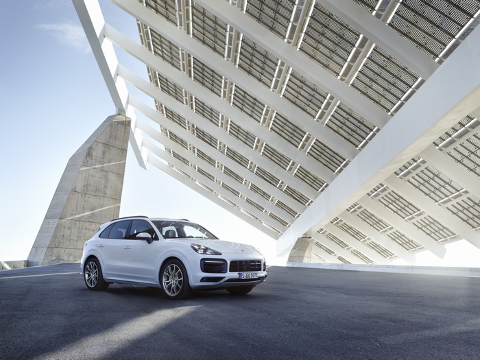 White Porsche Cayenne E-Hybrid SUV under solar panels