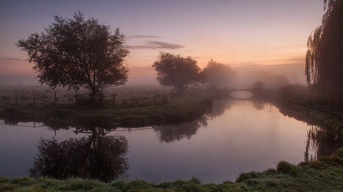 Misty river landscape at sunrise with a bridge