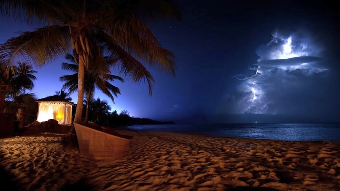Beach cabana and lightning storm over the ocean at night