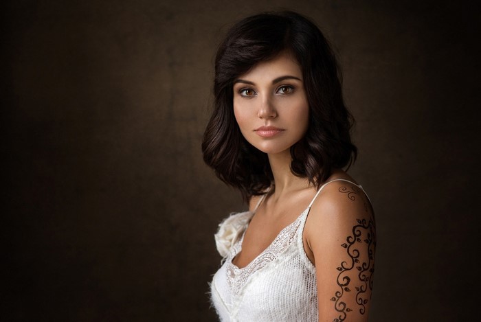 Woman with dark hair and tattoo in white dress