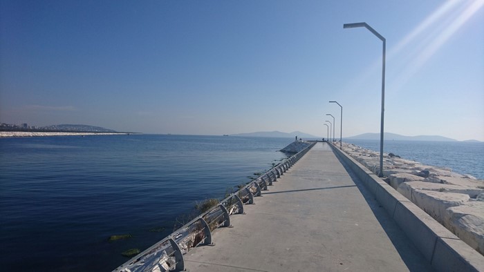 Concrete pier with modern lampposts extending into the sea
