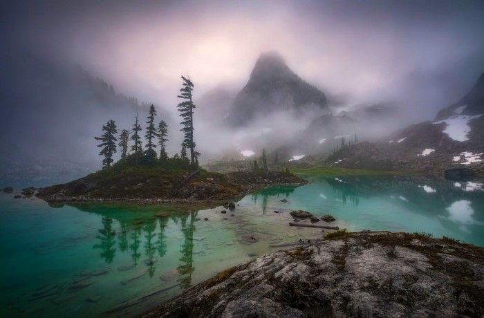 Misty mountain lake with island and trees