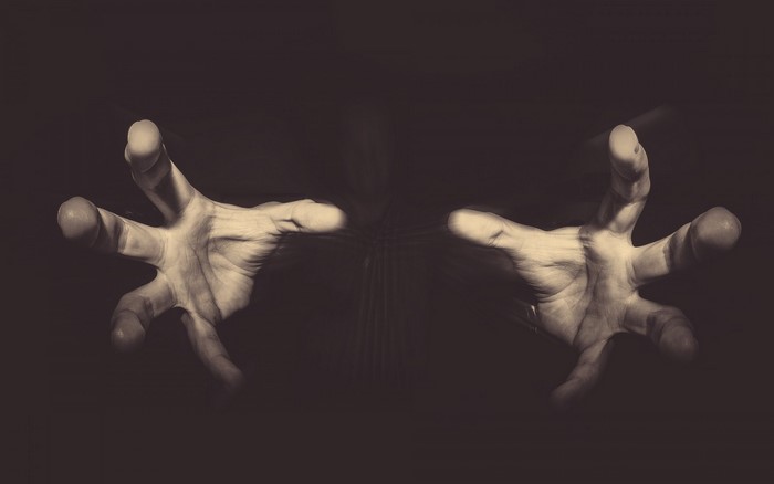 Two hands reaching out in darkness