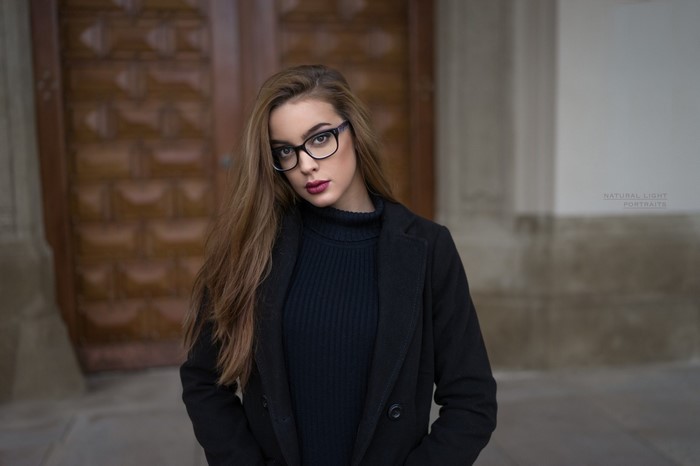 Woman with glasses wearing a black coat and turtleneck