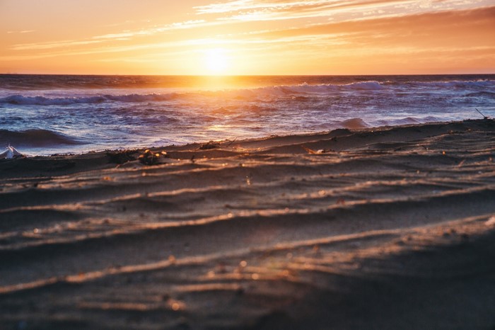 Sunset over the ocean with waves and sandy shore