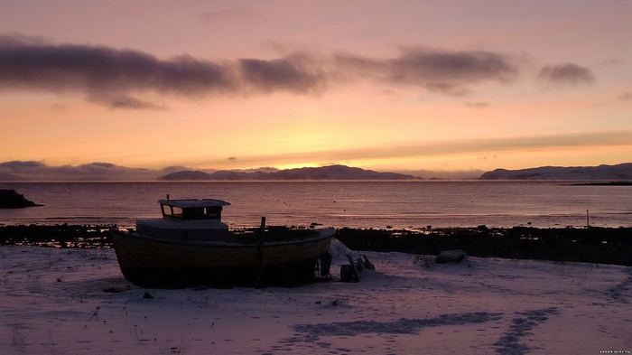 Boat on a snowy shore at sunset
