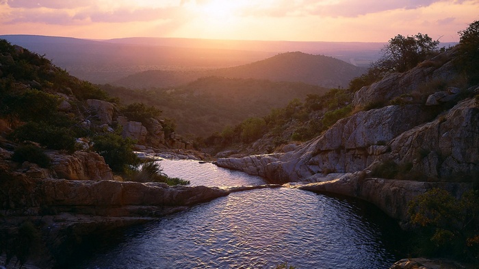 Sunset over rocky hills with cascading waterfalls