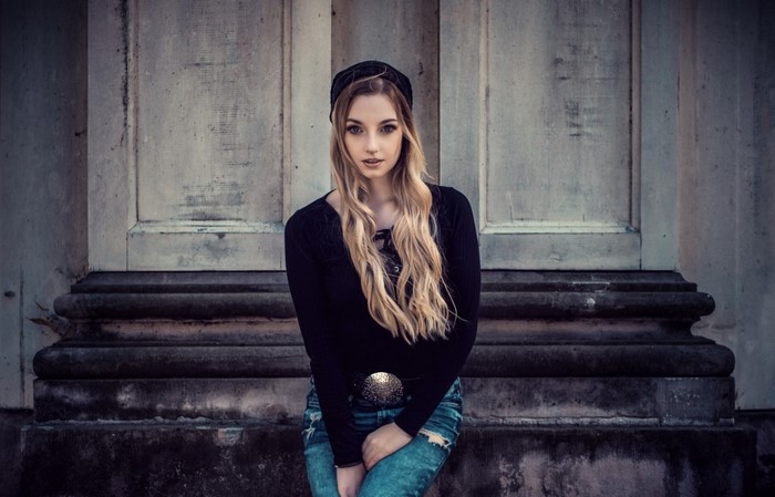 Woman with long blonde hair wearing a black beanie and black top