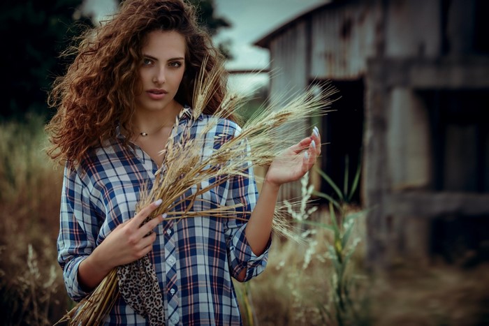 Woman with curly hair holding wheat stalks