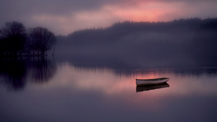 Boat on a misty lake at sunrise