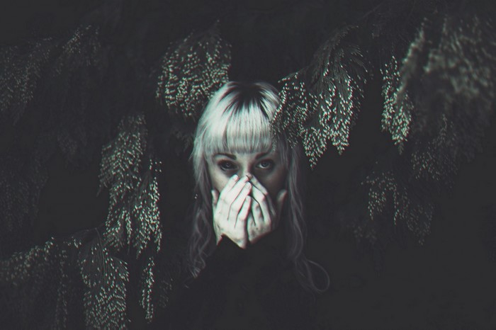 Woman with hands covering mouth in dark forest