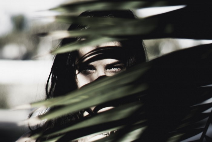 Woman peeking through dark leaves