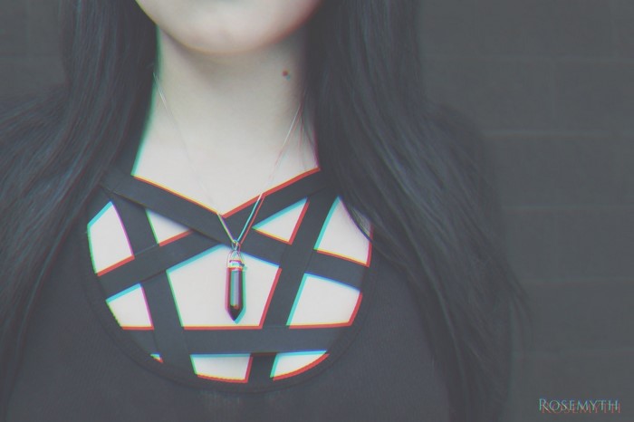 Woman wearing a black top with a pentagram design and a crystal pendant