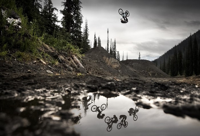 Mountain biker performing a flip over a puddle