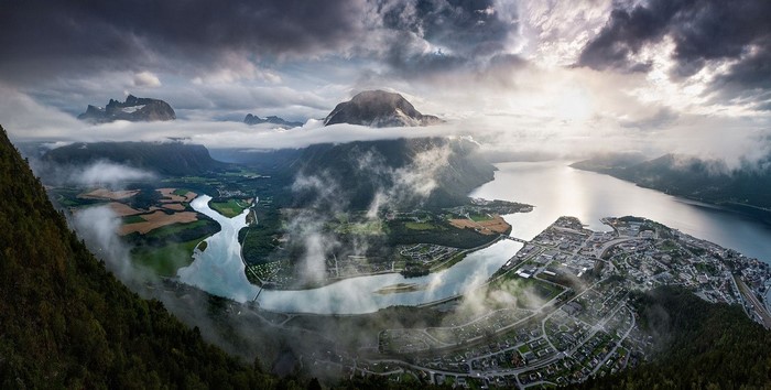 Panoramic view of a Norwegian fjord town with mountains and clouds