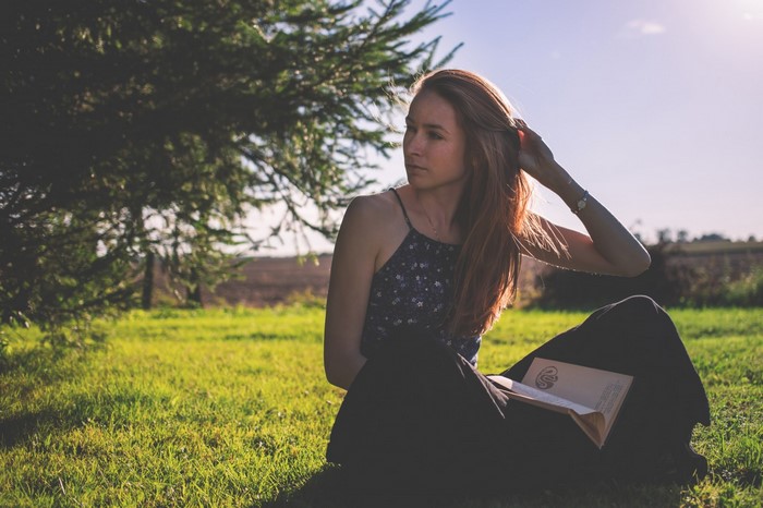 Woman sitting in grass reading a book