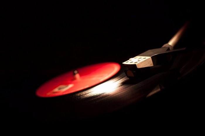 Close-up of a turntable needle on a red vinyl record