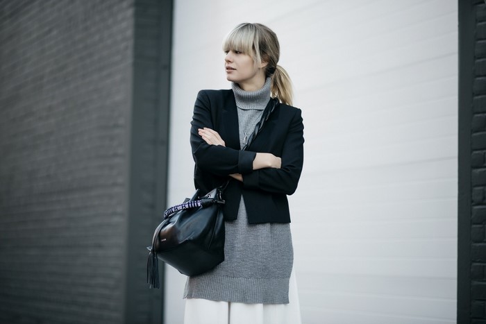 Woman wearing a black jacket and grey turtleneck