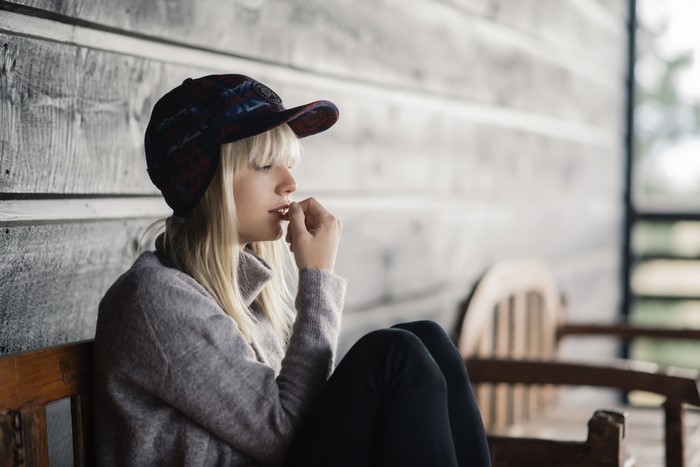 Woman wearing a patterned cap and sweater sitting on a bench