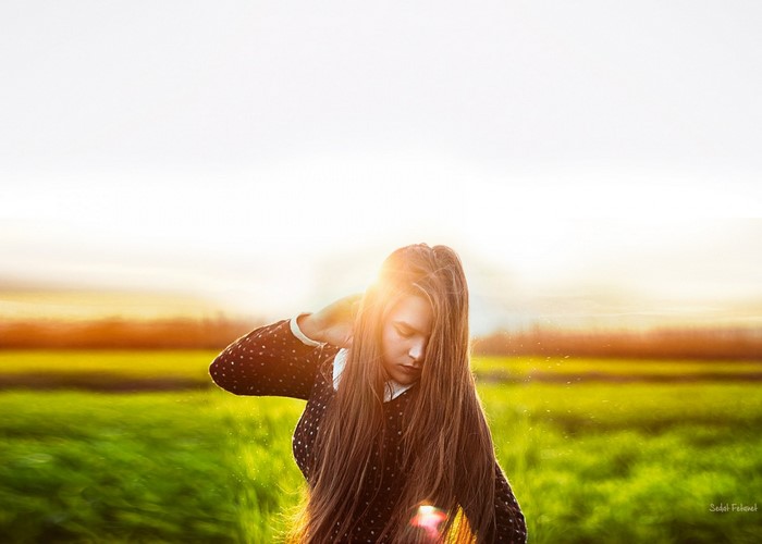 Young woman with long hair in a field at sunset