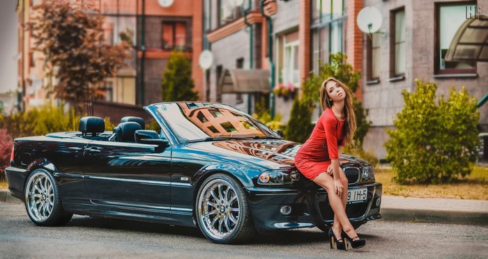 Woman in red dress sitting on a black BMW convertible