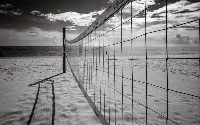 Monochrome beach volleyball net on sandy shore