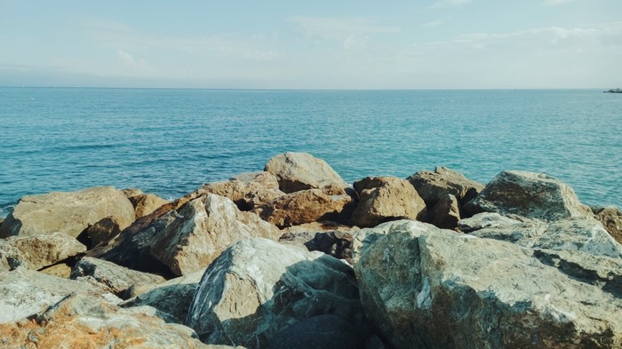 Rocks on the shore of the blue ocean under a clear sky
