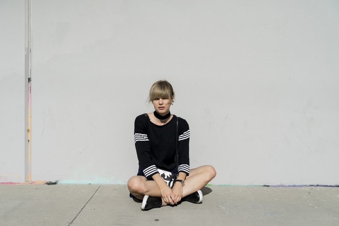 Woman in black Adidas outfit sitting on pavement