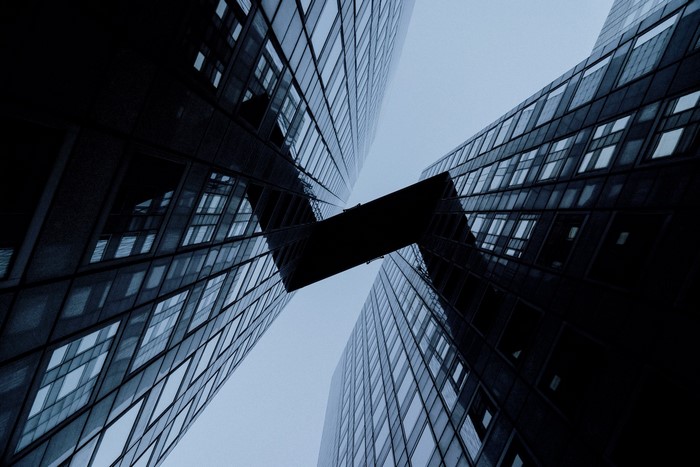 Two skyscrapers connected by a bridge against a blue sky