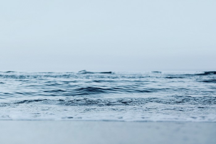 Ocean waves rolling onto a sandy shore under a clear sky