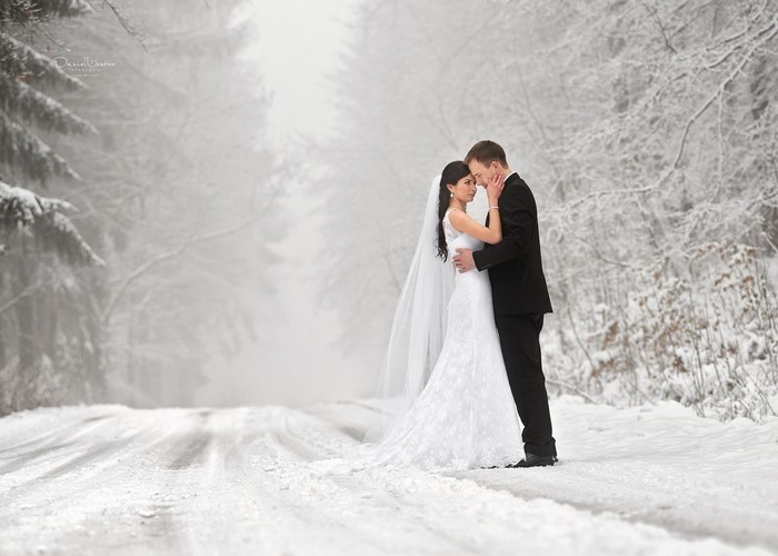 Bride and groom in a snowy forest road