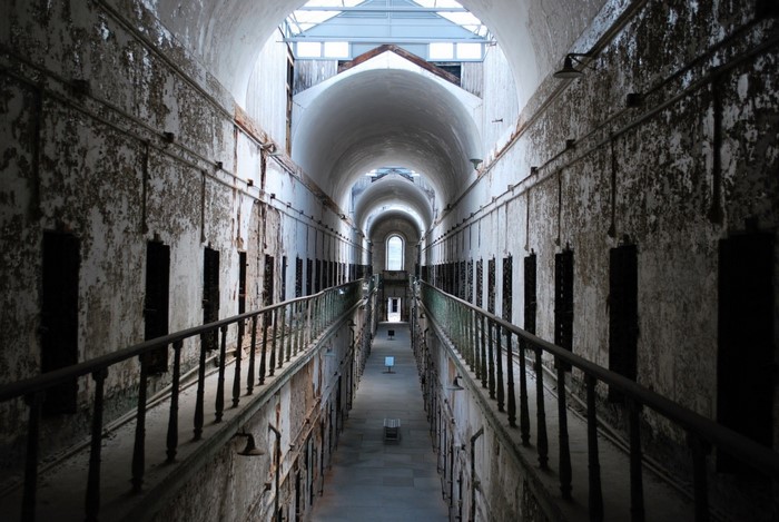 Abandoned prison hallway with cells and arched ceiling