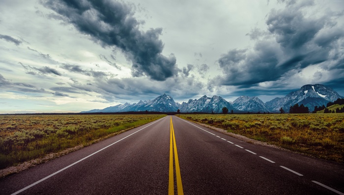Road leading to mountains under stormy clouds 4K