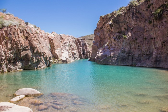 Turquoise water in a rocky canyon under a clear blue sky
