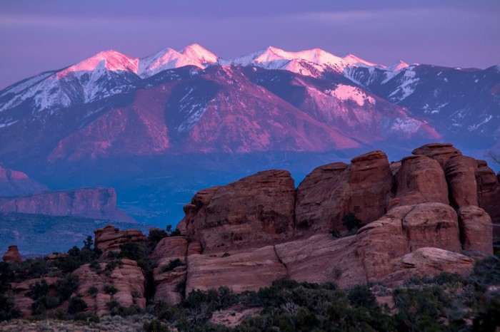 Pink-lit mountains and red rock formations at sunrise