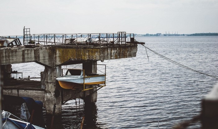 Boat suspended on a derelict pier over the water