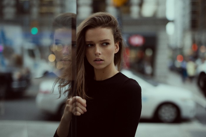 Woman looking away reflected in glass on a city street