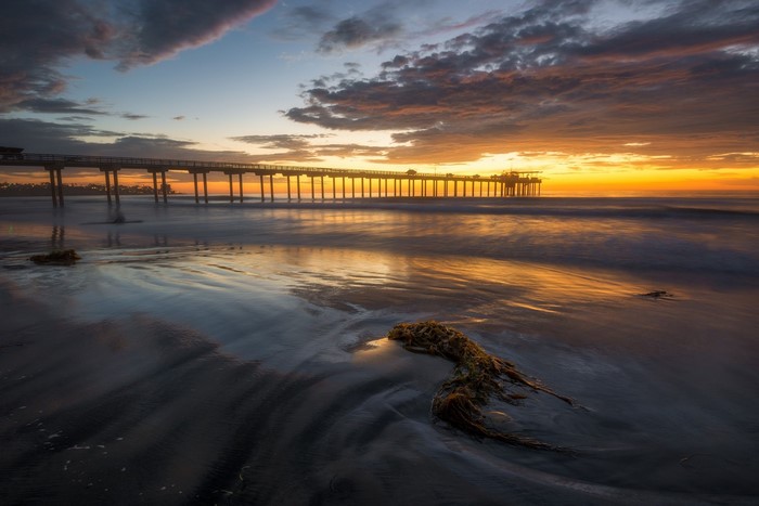 Sunset over Scripps Pier with ocean waves on the beach