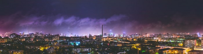 Panoramic cityscape at night with purple clouds