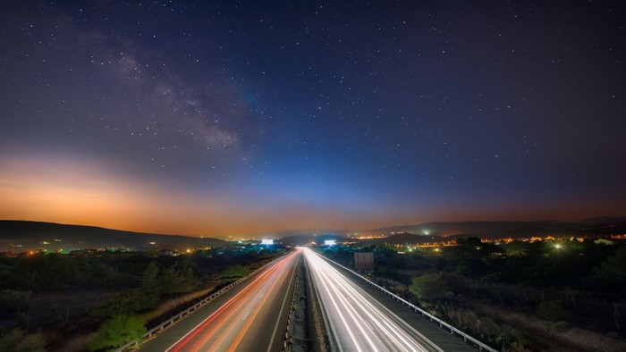 Highway at night with Milky Way and light trails