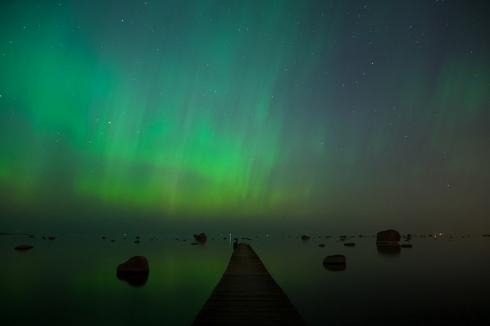 Aurora borealis over a calm sea with a pier
